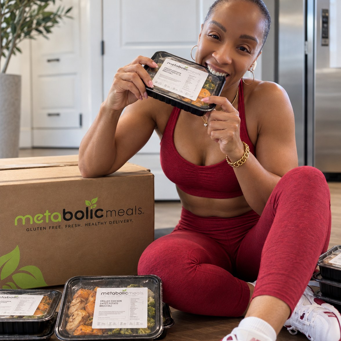 Dr. Shari smiling and holding a Metabolic Meals container, with a branded delivery box and more meals on the floor beside her